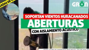 Fotografía promocional que muestra a un operario usando una herramienta eléctrica junto a grandes puertas corredizas de vidrio con vistas al mar y rótulos que resaltan resistencia a vientos y aislamiento acústico, pensada como imagen informativa y optimizada para Aberturas de PVC ventajas y desventajas para tu hogar