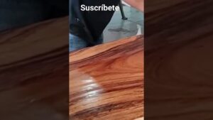 Fotograma vertical de un video que muestra una mesa de madera pulida con vetas oscuras y la parte superior de una persona junto al texto "Suscríbete", Ventajas y desventajas de uñas de gel: ¿valen la pena?