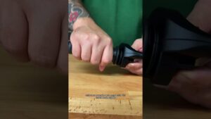 Primer plano de manos que agarran un acelerador de manillar negro sobre una mesa de madera, con un brazo tatuado y camiseta verde de fondo y subtítulos sobre la respuesta del motor, ideal para ilustrar Acelerador de cuarta ventajas y desventajas: ¿vale la pena?