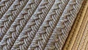 Detalle macro de una alfombra trenzada en tonos beige y gris con filas de cuerda entrelazadas y textura rugosa visible que facilita la comprensión táctil y la indexación web, Alfombras de polipropileno ventajas y desventajas para ti
