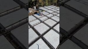 Imagen aérea de una estructura en obra que ilustra claramente Losa aligerada con casetón ventajas y desventajas para tu construcción, mostrando casetones rectangulares blancos encajados en una retícula de acero y varillas de refuerzo listos para el hormigonado, optimizada para accesibilidad y búsqueda con palabras clave sobre losas aligeradas y armado estructural.