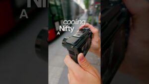 Primer plano de manos sujetando una cámara compacta negra con pantalla trasera y controles visibles sobre un fondo urbano desenfocado, imagen clara y útil para reseñas técnicas y comparativas Canon PowerShot SX540 HS ventajas y desventajas para decidir tu compra