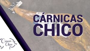 Fotografía de una pata de jamón curado con etiqueta y cordón, el gran rótulo morado CÁRNICAS CHICO y el logotipo en la esquina sobre fondo gris con una franja diagonal morada, ideal para ilustrar Ventajas y desventajas del cerdo duroc en tu producción.
