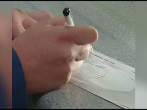 Primer plano de manos que sostienen un bolígrafo y rellenan o firman un documento bancario tipo cheque sobre una encimera, ilustrando visualmente el tema Cheque de gerencia ventajas y desventajas: ¿es seguro y conveniente? y proporcionando contexto descriptivo para accesibilidad y SEO.