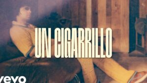 Imagen en tonos sepia de una persona reclinada en un sofá frente a un panel de madera con la palabra "UN CIGARRILLO" en tipografía grande y central, evocando un ambiente íntimo y contemplativo — Ventajas y desventajas de fumar IQOS: ¿vale la pena?