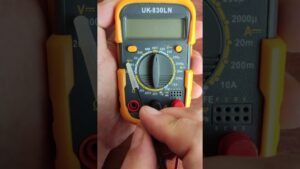 Multímetro digital portátil con carcasa protectora amarilla sostenido por una mano, pantalla LCD apagada, selector giratorio y entradas para sondas rojas y negras con una sonda cercana al dial que muestra el equipo en uso para pruebas eléctricas y seguridad, Ventajas y desventajas de un motor CC: potencia y limitaciones