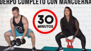 Un hombre y una mujer en ropa deportiva realizan sentadillas tipo sumo sujetando mancuernas frente a un muro de ladrillo blanco con un gráfico circular que señala treinta minutos; Ventajas y desventajas de hacer pesas en mujeres: lo que debes saber, descripción enfocada en técnica, agarre y beneficios del entrenamiento de cuerpo completo.