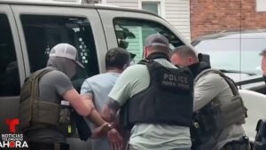 Varios agentes de policía con chalecos tácticos esposan a un hombre junto a una furgoneta en una detención callejera, Tlc Perú Estados Unidos ventajas y desventajas y su impacto real