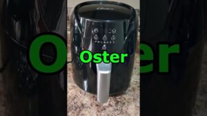 Fotografía de una freidora de aire Oster negra con acabado brillante, panel táctil con iconos, mango plateado y cable lateral sobre una encimera, optimizada para accesibilidad y SEO como alternativa visual para contenidos sobre Freidora de aire caliente ventajas y desventajas: ¿vale la pena?