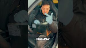 Persona con guantes azules sentada en el interior de un coche sostiene y señala un generador metálico de ozono apoyado en el regazo mientras en la imagen aparece la palabra HUMEDAD, Generador de ozono ventajas y desventajas: poder y riesgos clave