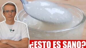 Profesional con bata blanca y micrófono a la izquierda mira serio mientras a la derecha un cuenco transparente contiene un gel blanco que se muestra con una cuchara sobre una franja roja con la pregunta "¿Esto es sano?", ilustrando Ventajas y desventajas de la goma xantana: lo esencial que debes saber