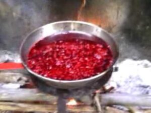 Sartén metálica sobre fuego de leña con una mezcla roja espesa y grumosa hirviendo y soltando vapor en un entorno rústico, Harina de sangre ventajas y desventajas: beneficios y riesgos clave.