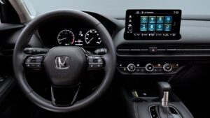Vista interior del Honda HR-V con volante multifunción y emblema Honda, cuadro de instrumentos digital, pantalla táctil central con menús, controles de climatización y palanca de cambios en consola central, materiales en tonos oscuros y diseño moderno y práctico — Ventajas y desventajas de Honda HR-V: ¿es el SUV ideal para ti?