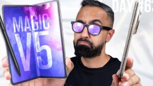 Un hombre con barba y gafas sostiene frente al espectador dos teléfonos plegables —uno abierto con pantalla interior brillante que muestra las palabras "MAGIC V5" y un lápiz táctil, y otro cerrado para comparar grosor y diseño— en una imagen pensada para analizar smartphones plegables y revisar Ventajas y desventajas Honor Magic 7 Lite: ¿vale la pena?