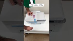 Impresora multifunción blanca de la marca HP colocada sobre una mesa blanca, capturada en primer plano mientras manos adultas retiran cintas y sellos protectores durante el desempaquetado, descripción accesible y optimizada para búsquedas y comparativas como Hp Smart Tank 580 ventajas y desventajas para decidir si es para ti