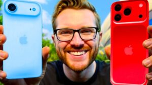 Hombre sonriente con gafas y barba sostiene en primer plano dos iPhone de colores contrastantes, azul claro y rojo, con fondo exterior desenfocado para ilustrar una comparativa visual y reseña técnica orientada a búsquedas sobre iPhone y actualizaciones; Ventajas y desventajas de iOS 17: ¿vale la pena actualizar?