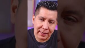 Primer plano de un hombre adulto con cabello oscuro y camiseta negra, mirada seria y ligera inclinación de cabeza sobre un fondo difuminado en tonos morados, adecuado para ilustrar contenido titulado Qué es la morfina ventajas y desventajas: efectos y riesgos clave.