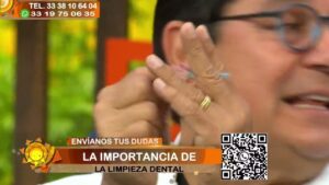 Primer plano de un presentador de un programa matutino que gesticula y sostiene una pequeña herramienta junto al rostro, con un rótulo informativo que dice LA IMPORTANCIA DE LA LIMPIEZA DENTAL y la leyenda ENVÍANOS TUS DUDAS, logotipo de sol, código QR y números de contacto visibles en pantalla, Limpieza dental con ultrasonido: ventajas y desventajas reales