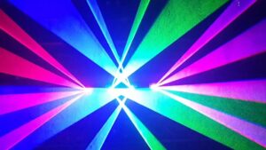 Patrón radial simétrico de haces de luz en tonos azul, verde, magenta y fucsia que irradian desde un punto central sobre un fondo oscuro, con líneas nítidas y alto contraste que evocan efectos de iluminación LED; Ventajas y desventajas de luces led en autos: ¿valen la pena?