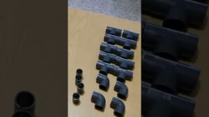 Vista cenital de piezas de tubería de PVC gris — codos, tes y acoples — ordenadas en filas sobre una mesa de madera, Muebles de PVC ventajas y desventajas: ¿son la mejor opción?