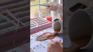 Manos frente a una ventana, con un teléfono en una mano y una taza volcada derramando café sobre un planificador o bullet journal decorado con rotuladores y accesorios rosas, una escena que visualiza My Study Life ventajas y desventajas para organizar tu estudio y subraya la necesidad de proteger y hacer accesibles tus materiales.