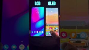 Comparativa visual accesible mostrando dos teléfonos colocados lado a lado con etiquetas en la parte superior 'LCD' y 'OLED', donde la pantalla izquierda presenta un degradado púrpura-azul más apagado y la derecha muestra colores cálidos y mayor contraste en una escena de carretera, con dedos sujetando los dispositivos y iconos de aplicaciones visibles, Ventajas y desventajas de pantalla LCD: ¿es la opción ideal?