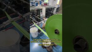 Línea de producción industrial con bobinas y rodillos alimentando una banda de papel kraft de color verde junto a cubetas y mecanismos, Ventajas y desventajas del papel kraft: ¿es la opción ideal?