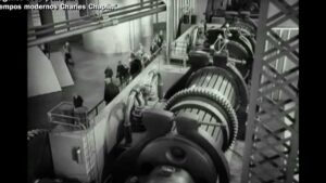 Fotografía en blanco y negro de una planta industrial con grandes cilindros y engranajes alineados, pasarelas y personas junto a la maquinaria vista en perspectiva angular, descripción optimizada para accesibilidad y SEO, Ventajas y desventajas del sistema MTM para optimizar tu productividad.