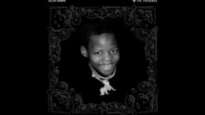 Retrato en blanco y negro de un niño sonriente centrado sobre un fondo negro con un grueso collar con un colgante en forma de figura animal y un marco decorativo tipo bandana, optimizado para accesibilidad y SEO; Ventajas y desventajas de Spin by Oxxo: ¿vale la pena usarla?