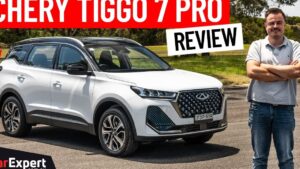 Imagen de un Chery Tiggo 7 Pro blanco con techo negro, parrilla cromada y llantas de aleación aparcado en un entorno al aire libre junto a un hombre de pie con los brazos cruzados, diseñada como miniatura de reseña que incluye la pregunta Tiggo 7 Pro ventajas y desventajas: ¿vale la pena este SUV?