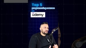 Hombre hablando frente a un micrófono profesional en un retrato tipo podcast sobre un fondo azul cuadriculado que muestra el logo de Udemy y el texto en inglés "Top 5 programming courses on udemy", Ventajas y desventajas de la plataforma Udemy: ¿vale la pena?